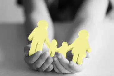 Hands holding a paper cut out of a family