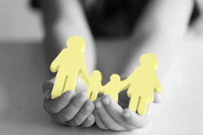 Hands holding a paper cut out of a family