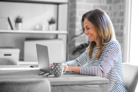 Woman types and smiles at laptop